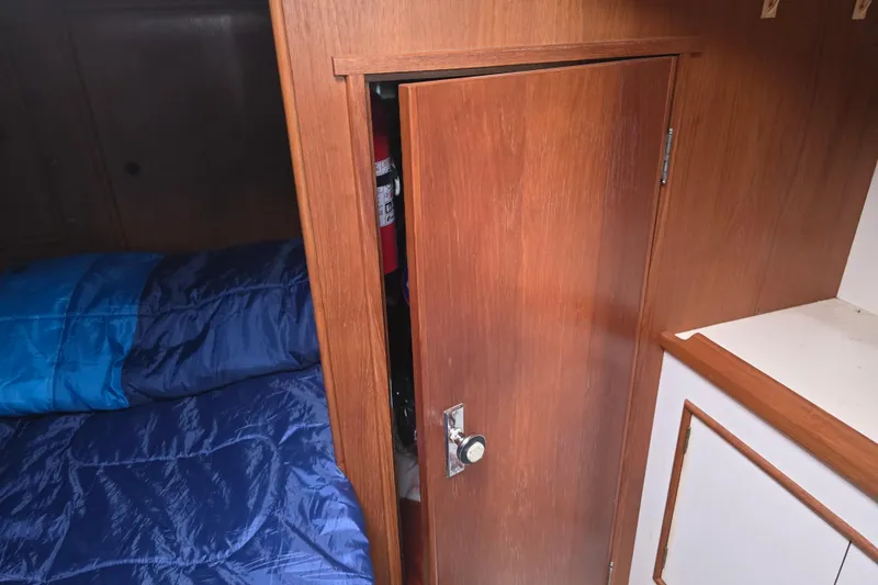 Slide: The Image of Cozy cabin interior of 1987 Nonsuch 30 Ultra sailboat with wooden door and blue bedding. - 26