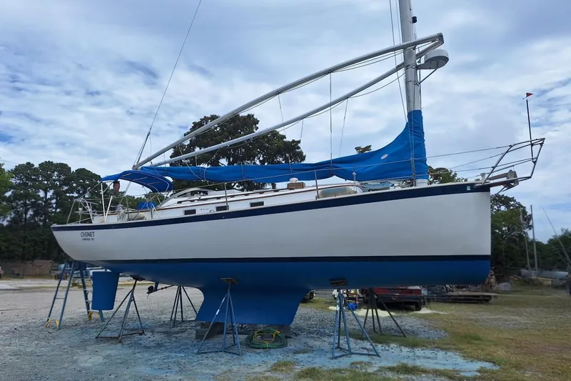 Slide: The Image of 1987 Nonsuch 30 Ultra sailboat on stands, blue and white hull, outdoor setting. - 7
