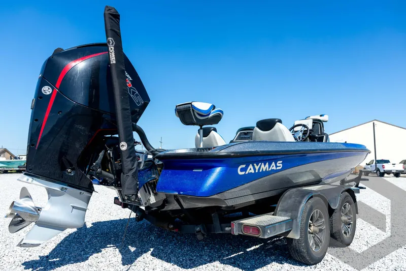 Slide: The Image of 2023 Caymas CX19 boat with blue accents on a trailer, parked on gravel. - 16