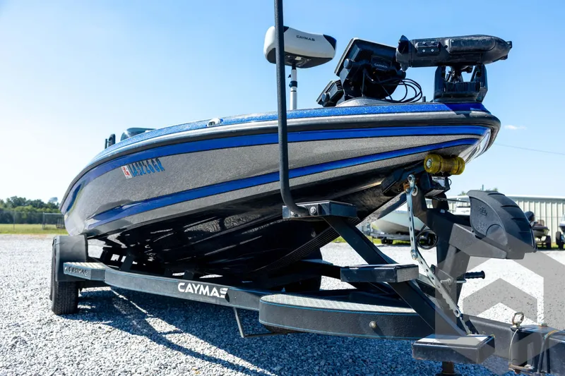 Slide: The Image of 2023 Caymas CX19 boat with dual axle trailer, blue and gray design, parked on gravel. - 9