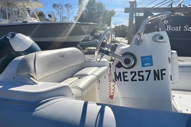 Slide: The Image of 2007 Caribe 15DL boat with white seating and steering wheel, docked in sunlight. - 15