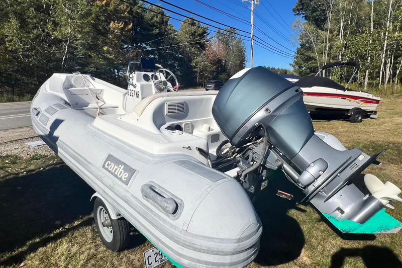 Slide: The Image of 2007 Caribe 15DL inflatable boat with outboard motor on a trailer, parked outdoors. - 4