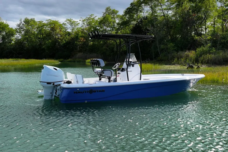 Slide: The Image of 2026 NauticStar 214 Bay boat on calm water, surrounded by lush greenery. - 3