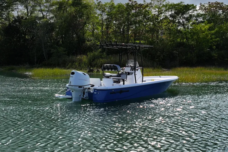 Slide: The Image of 2026 NauticStar 214 Bay boat on calm water near lush greenery. - 4
