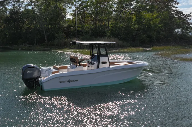 Slide: The Image of 2026 NauticStar 242 Offshore boat on serene water, surrounded by lush greenery. - 7