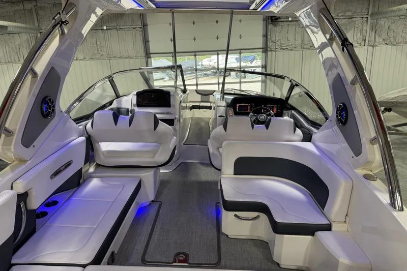 Slide: The Image of 2019 Chaparral 347 SSX boat interior with modern seating and dashboard in a garage. - 7
