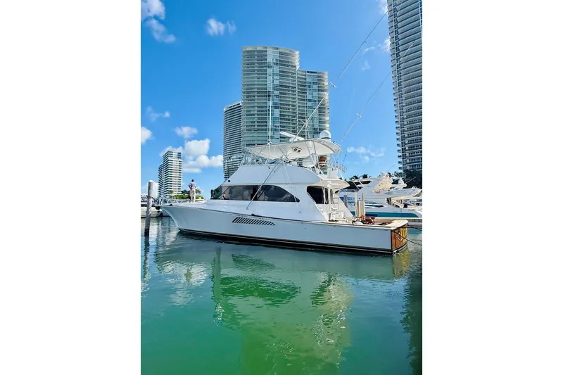 Slide: The Image of 2004 Viking 65 Convertible yacht docked near modern high-rise buildings. - 1