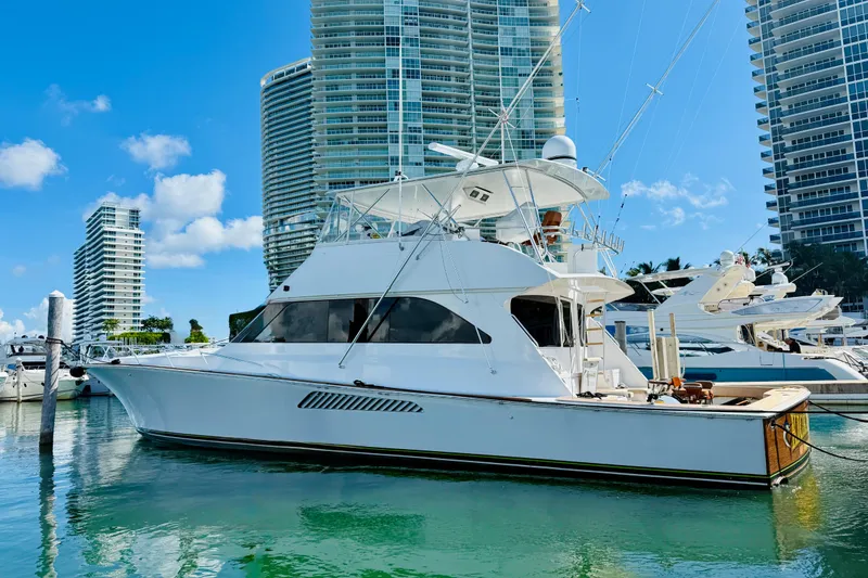 Slide: The Image of 2004 Viking 65 Convertible yacht docked in a marina with skyscrapers in the background. - 2