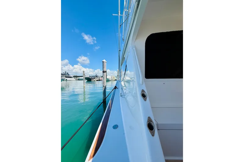 Slide: The Image of 2004 Viking 65 Convertible yacht docked in a serene marina under clear blue skies. - 6