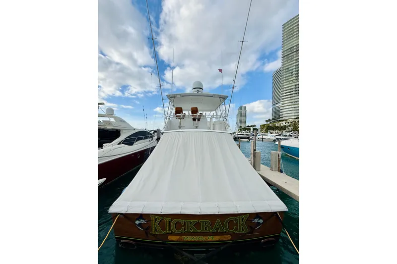 Slide: The Image of 2004 Viking 65 Convertible yacht docked, named "Kickback," with cityscape background. - 67