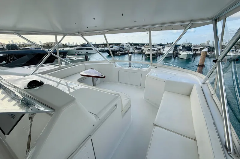 Slide: The Image of 2004 Viking 65 Convertible yacht interior with marina view, featuring white seating and table. - 75