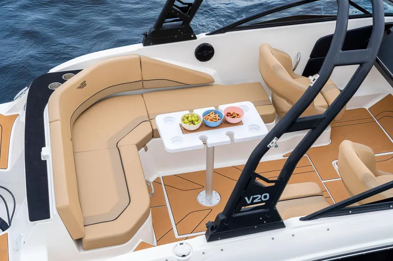 Slide: The Image of Manufacturer Provided Image: 2025 Bayliner V20 boat interior with tan seating, table, and snacks on a calm sea. - 7