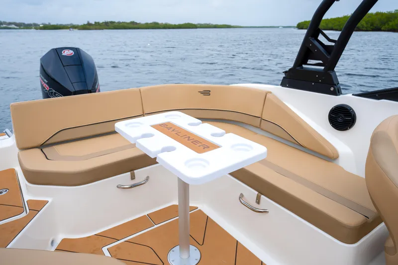 Slide: The Image of 2026 Bayliner V20 boat interior with tan seating and table on a calm lake. - 8