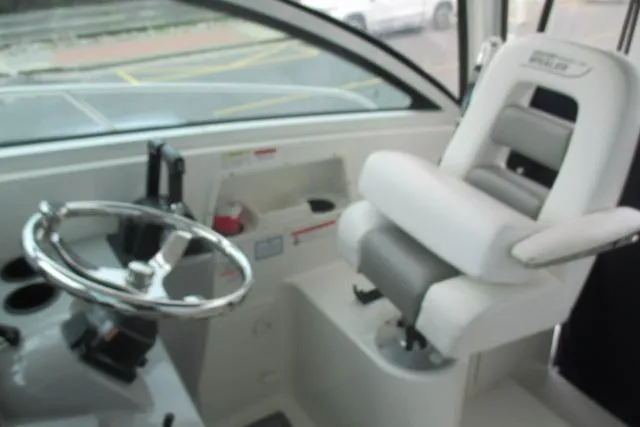 Slide: The Image of 2013 Boston Whaler 315 Conquest boat seat with white upholstery and cup holders. - 14