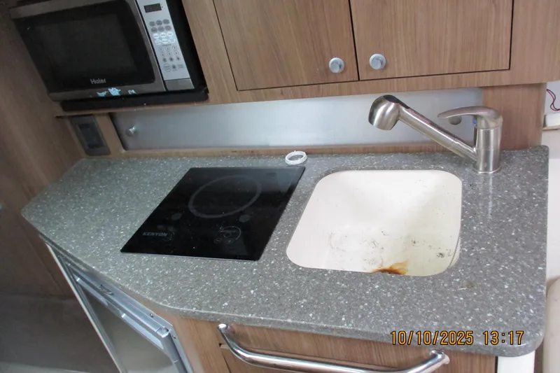 Slide: The Image of 2013 Boston Whaler 315 Conquest kitchenette with sink, stovetop, and microwave. - 24
