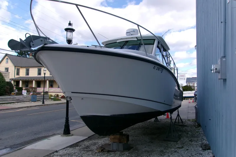 Slide: The Image of 2013 Boston Whaler 315 Conquest boat on dry dock near a building. - 28