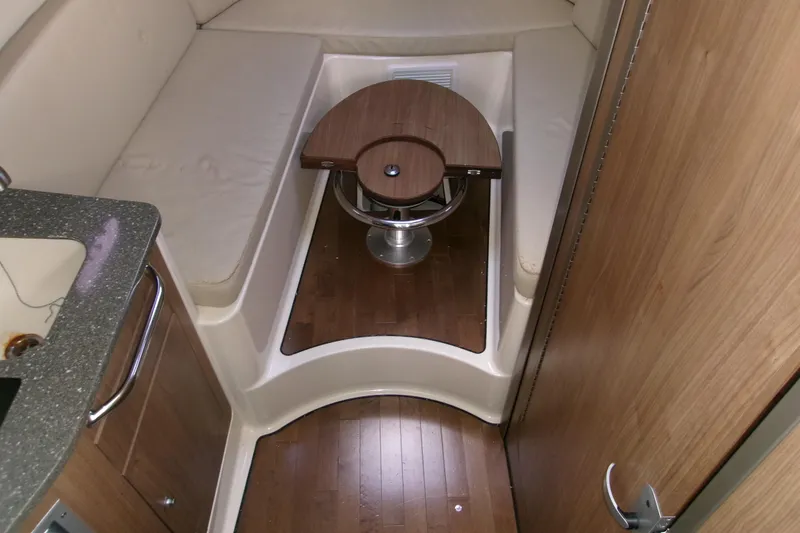 Slide: The Image of 2013 Boston Whaler 315 Conquest cabin interior with wooden flooring and compact seating area. - 37