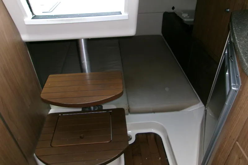 Slide: The Image of 2013 Boston Whaler 315 Conquest cabin interior with wooden steps and compact sleeping area. - 38