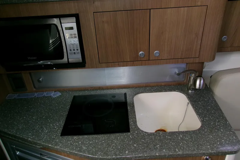Slide: The Image of 2013 Boston Whaler 315 Conquest kitchen with microwave, sink, and stovetop. - 40