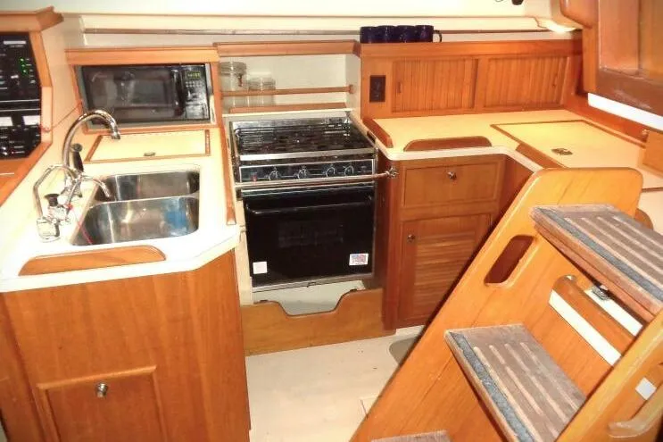 Slide: The Image of Island Packet 420 yacht kitchen interior with wooden cabinetry, stove, sink, and microwave, 2002 model. - 6