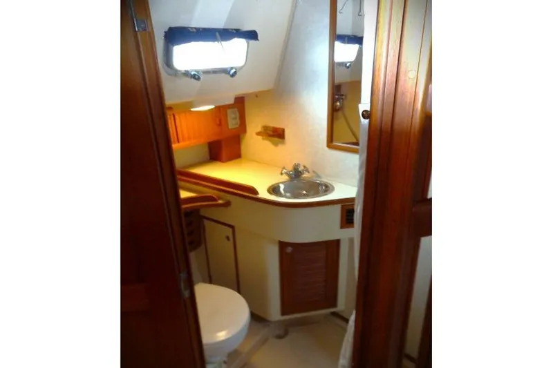 Slide: The Image of Island Packet 420 yacht bathroom interior, featuring sink, mirror, and wooden cabinetry, 2002 model. - 8