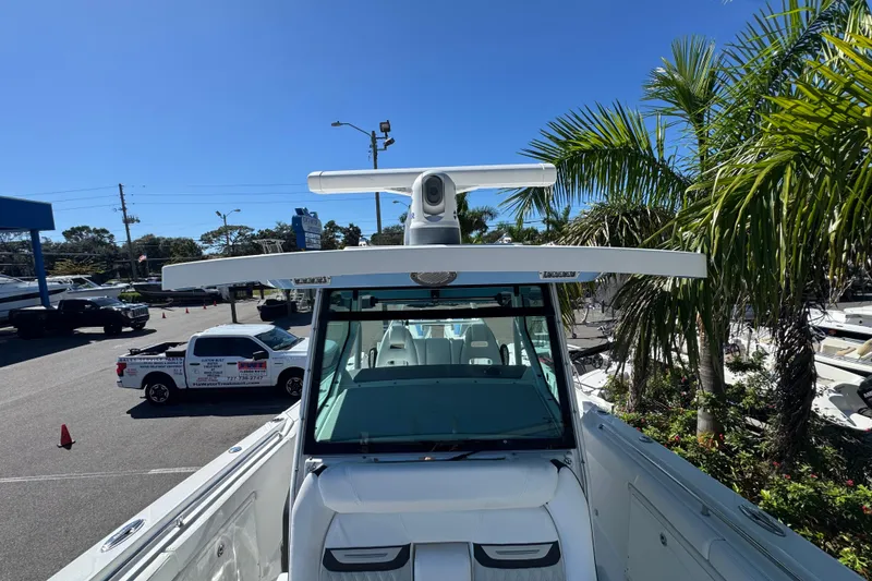 Slide: The Image of 2021 Blackfin 332 CC boat with radar, parked near palm trees and vehicles. - 27