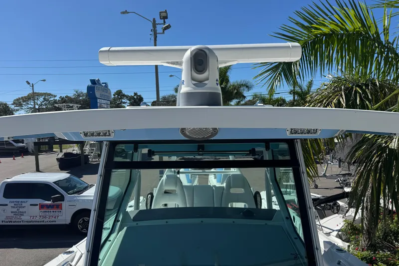 Slide: The Image of 2021 Blackfin 332 CC boat with radar, parked near palm trees and a service vehicle. - 28