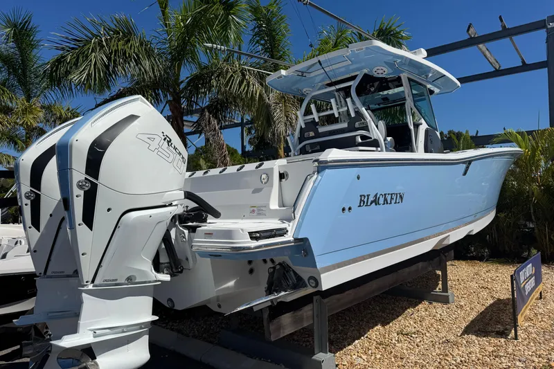 Slide: The Image of 2021 Blackfin 332 CC boat with twin engines, displayed outdoors with palm trees. - 3