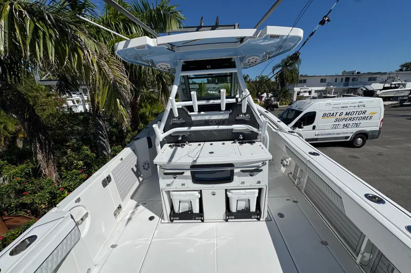 Slide: The Image of 2021 Blackfin 332 CC boat interior with fishing setup, parked near palm trees and a service van. - 8