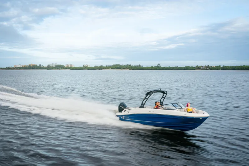 The Image of 2026 Bayliner VR6 Bowrider OB cruising on a serene lake under a cloudy sky. - 1