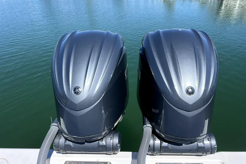 Slide: The Image of Twin Yamaha outboard engines on a 2024 Contender 32 ST boat, docked on calm water. - 16