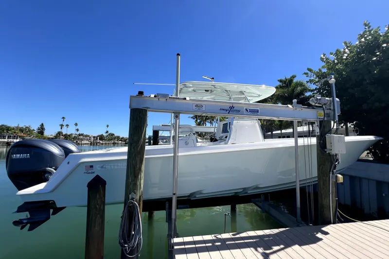 Slide: The Image of 2024 Contender 32 ST boat on lift with Yamaha engines, clear blue sky background. - 2
