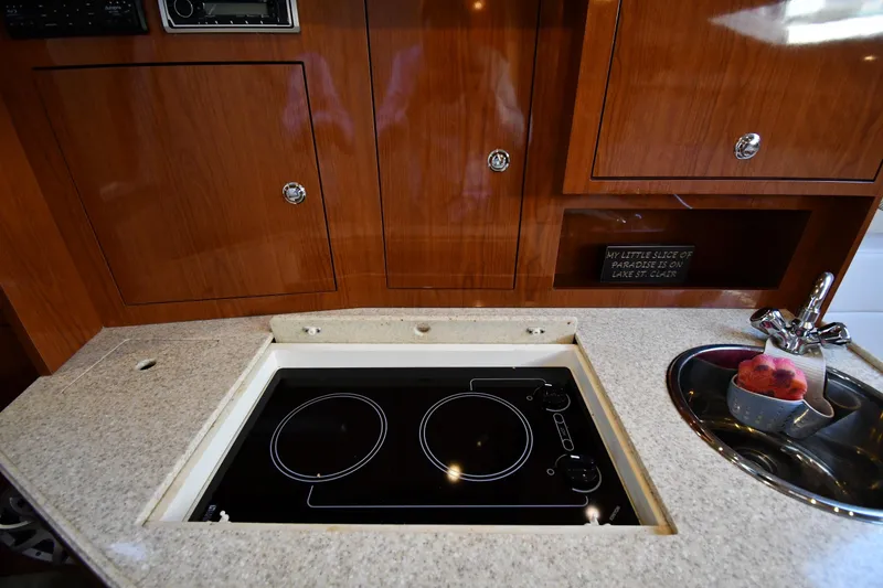 Slide: The Image of 2005 Regal 3060 Window Express yacht kitchen with stove, sink, and wooden cabinetry. - 33