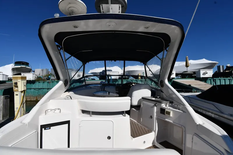 Slide: The Image of 2005 Regal 3060 Window Express boat docked, featuring spacious cockpit and covered seating area. - 8