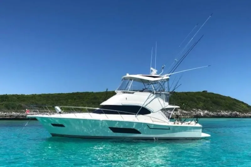 The Image of 2018 Riviera 43 Open Flybridge yacht in clear turquoise waters, scenic island backdrop. - 1