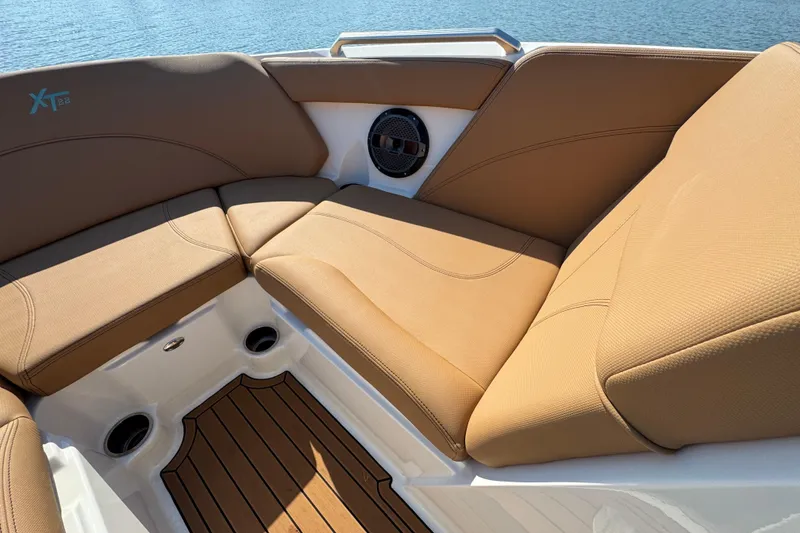 Slide: The Image of 2021 MasterCraft XT22 boat interior with tan seating and wood flooring, overlooking water. - 10