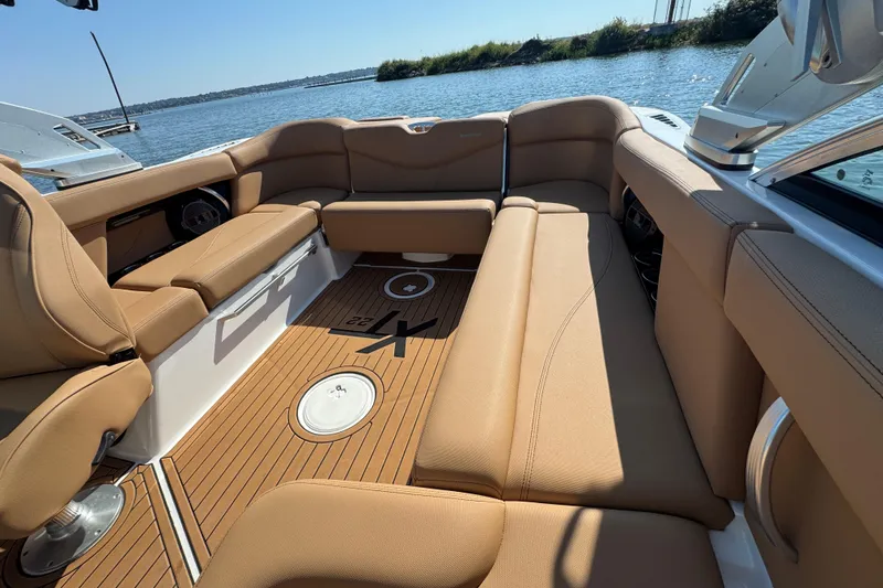 Slide: The Image of 2021 MasterCraft XT22 boat interior with tan seating and wood flooring by the water. - 20