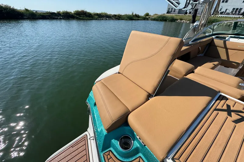 Slide: The Image of 2021 MasterCraft XT22 boat with tan seating, docked by a serene lake. - 24