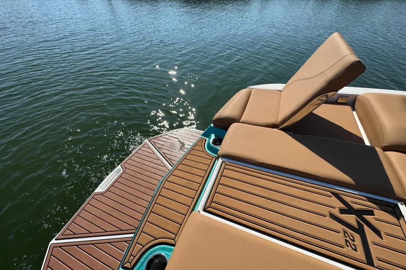 Slide: The Image of 2021 MasterCraft XT22 boat with tan seating and teak deck on water. - 25