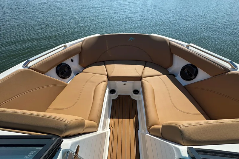 Slide: The Image of 2021 MasterCraft XT22 boat interior with tan seating and teak flooring on a calm lake. - 9