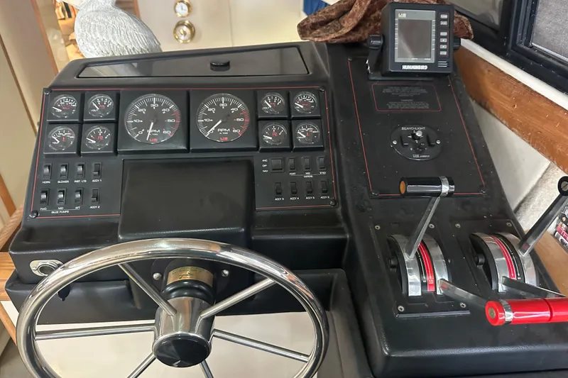 Slide: The Image of 1990 Bayliner 4388 Motoryacht helm with gauges, steering wheel, and control levers. - 17