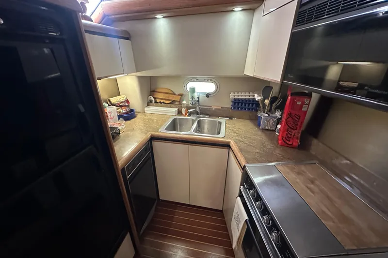 Slide: The Image of Compact kitchen in a 1990 Bayliner 4388 Motoryacht with modern amenities and wooden flooring. - 24