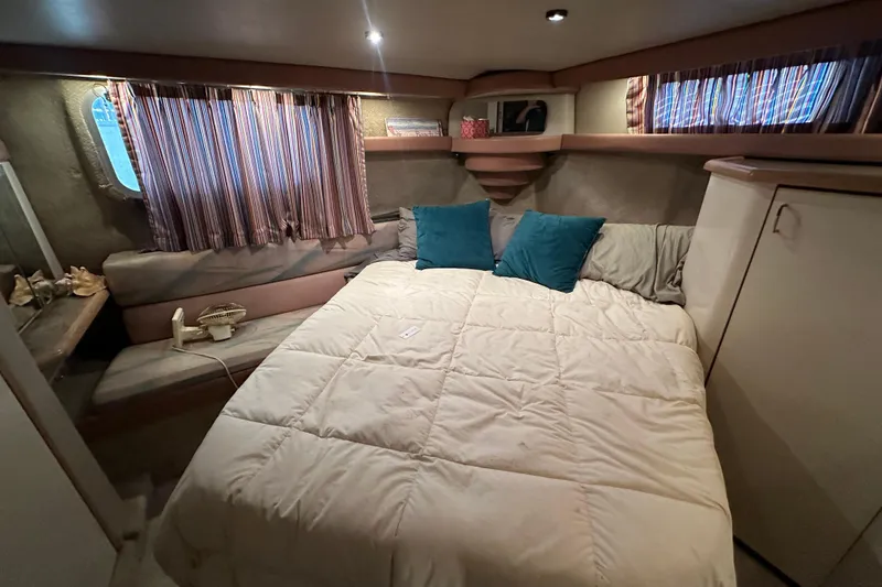 Slide: The Image of Cozy bedroom in 1990 Bayliner 4388 Motoryacht with bed, pillows, and striped curtains. - 36
