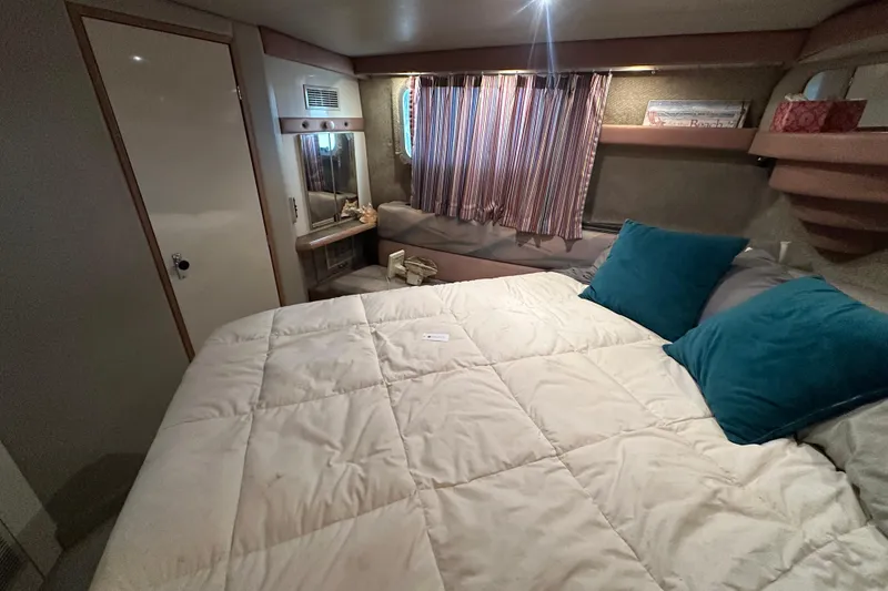 Slide: The Image of Cozy bedroom in 1990 Bayliner 4388 Motoryacht with striped curtains and teal pillows. - 40