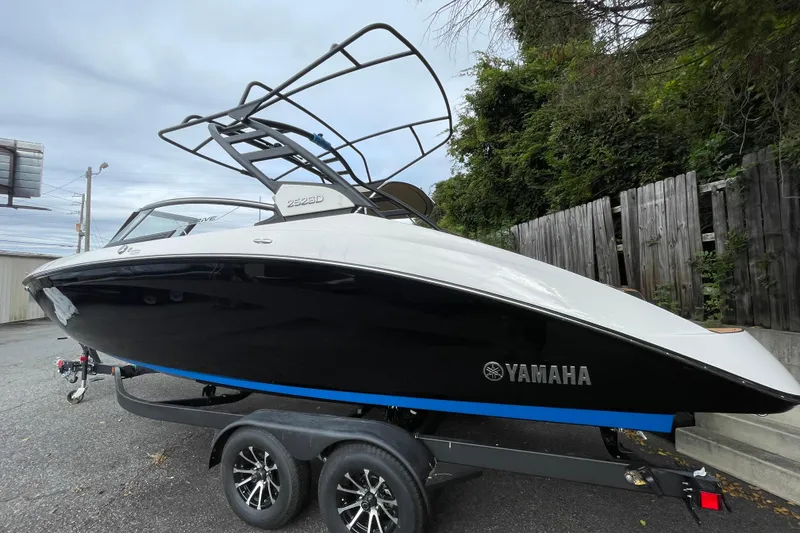 Slide: The Image of 2026 Yamaha Boats 252SD on trailer, sleek black and white design, parked outdoors. - 2