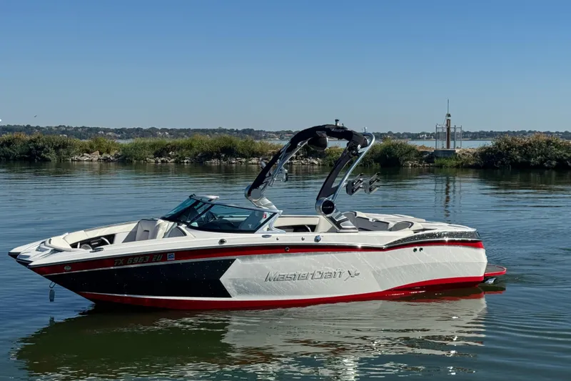 The Image of 2018 MasterCraft XStar boat on calm water, featuring sleek design and vibrant colors. - 1