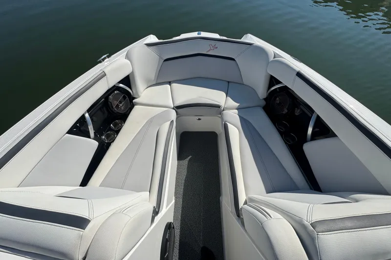 Slide: The Image of 2018 MasterCraft XStar boat interior with plush seating and cup holders on calm water. - 12