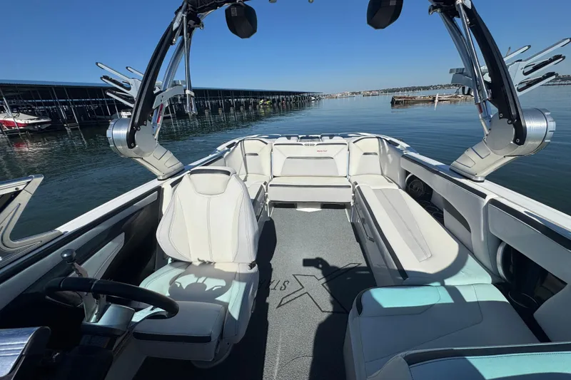 Slide: The Image of 2018 MasterCraft XStar boat interior with white seating and sleek design on calm water. - 13