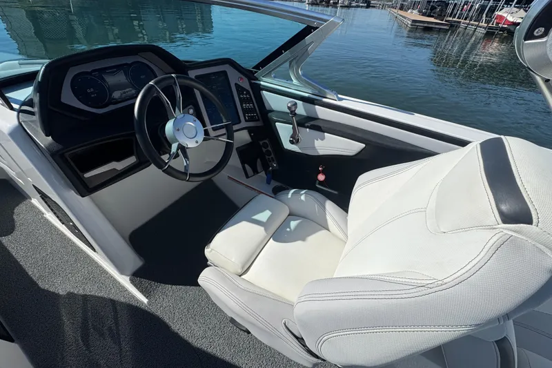 Slide: The Image of 2018 MasterCraft XStar boat interior with steering wheel and dashboard, docked by the water. - 15