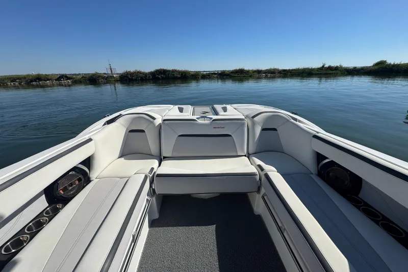 Slide: The Image of 2018 MasterCraft XStar boat interior with white seating, on calm water. - 21